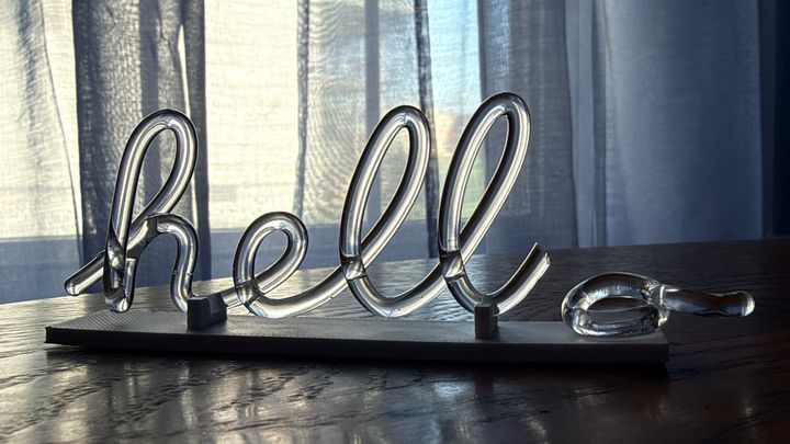 An acrylic sign that is meant to spell "hello" in cursive, but the "o" broke off