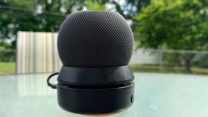A black HomePod mini in a battery base on an outdoor patio table