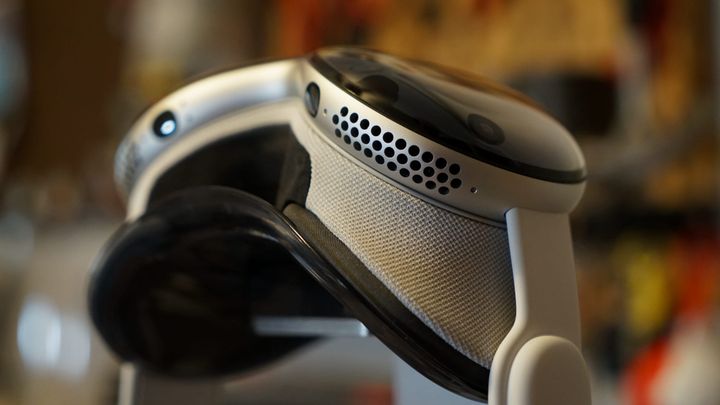Apple Vision Pro on a stand with a blurred out office background