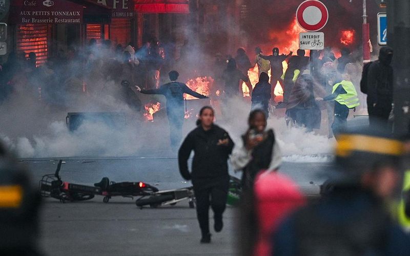 Protesters run from tear gas and street fires in Paris.