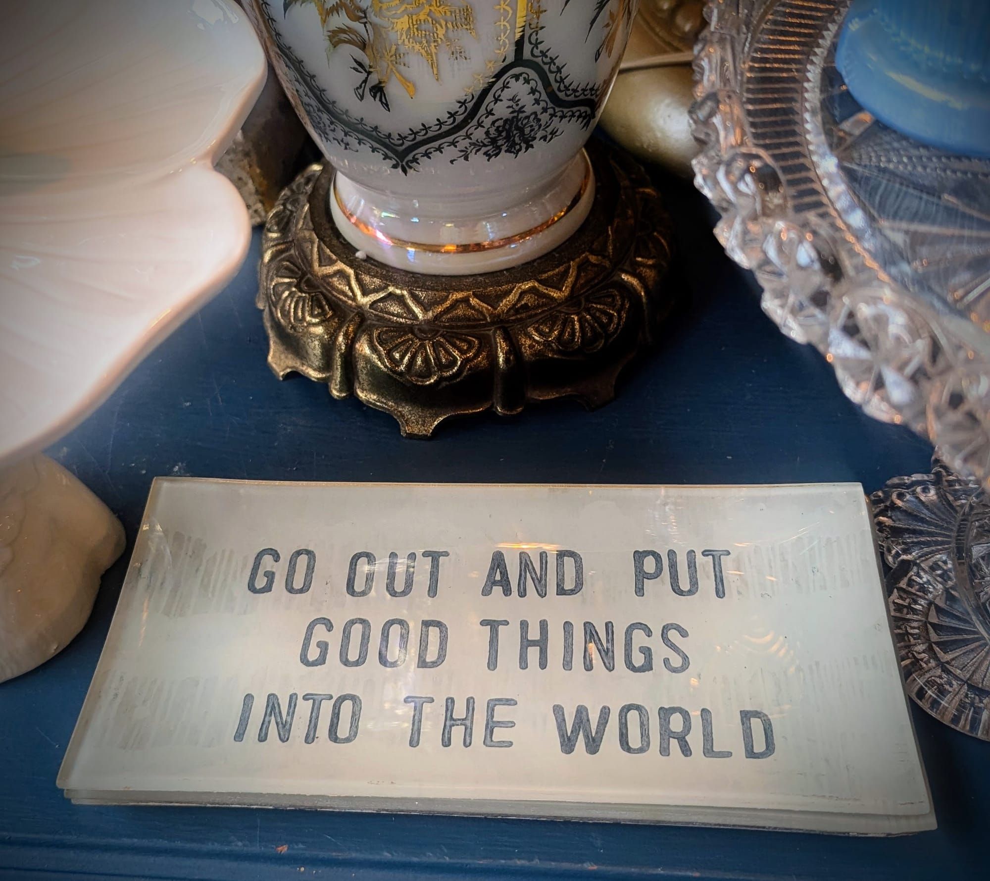 Glass plate on table that reads 'Go Out and Put Good Things Into The World'