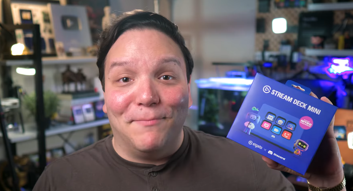 Andrew Kan holds up the Elgato Stream Deck Mini Discord Edition box with Discord Nitro promo in his studio.