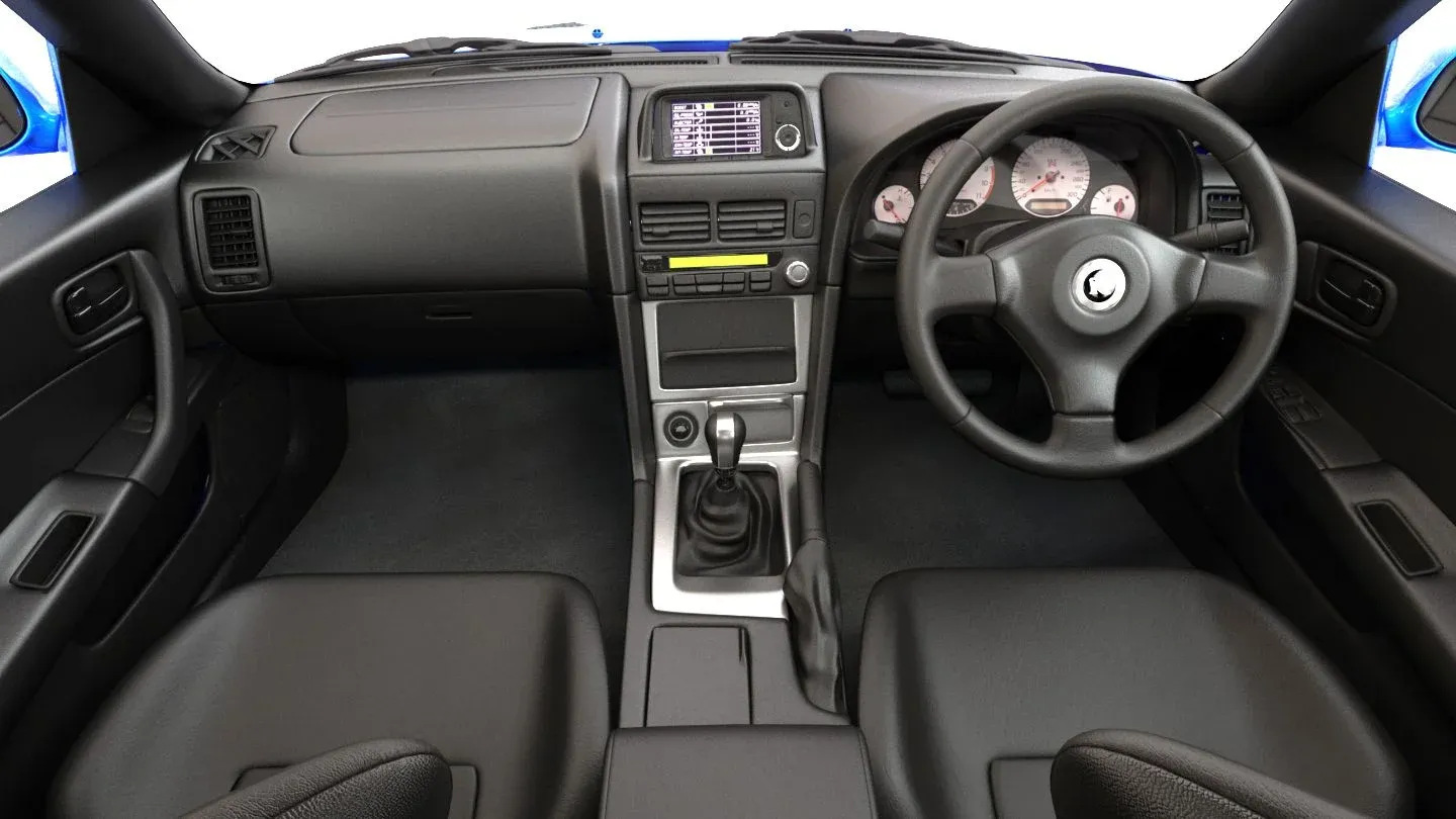 Cockpit de un Nissan Skyline GTR R34, destacando la pantalla multifunción (MFD) y los asientos deportivos.