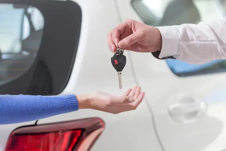Entrega de llave autos a una persona y fondo un auto blanco