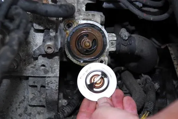 Mano sosteniendo termostato en buenas condiciones al lado de uno en mal estado