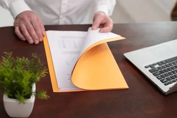 Persona abriendo carpeta con documentos dentro