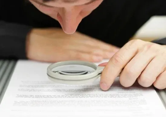 Persona observando por medio de una lupa un documento