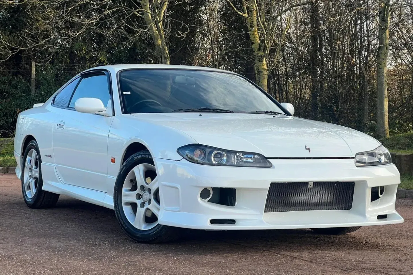 Un Nissan Silvia S15 Spec-R de color blanco, en perfecto estado y aparcado en un entorno urbano.