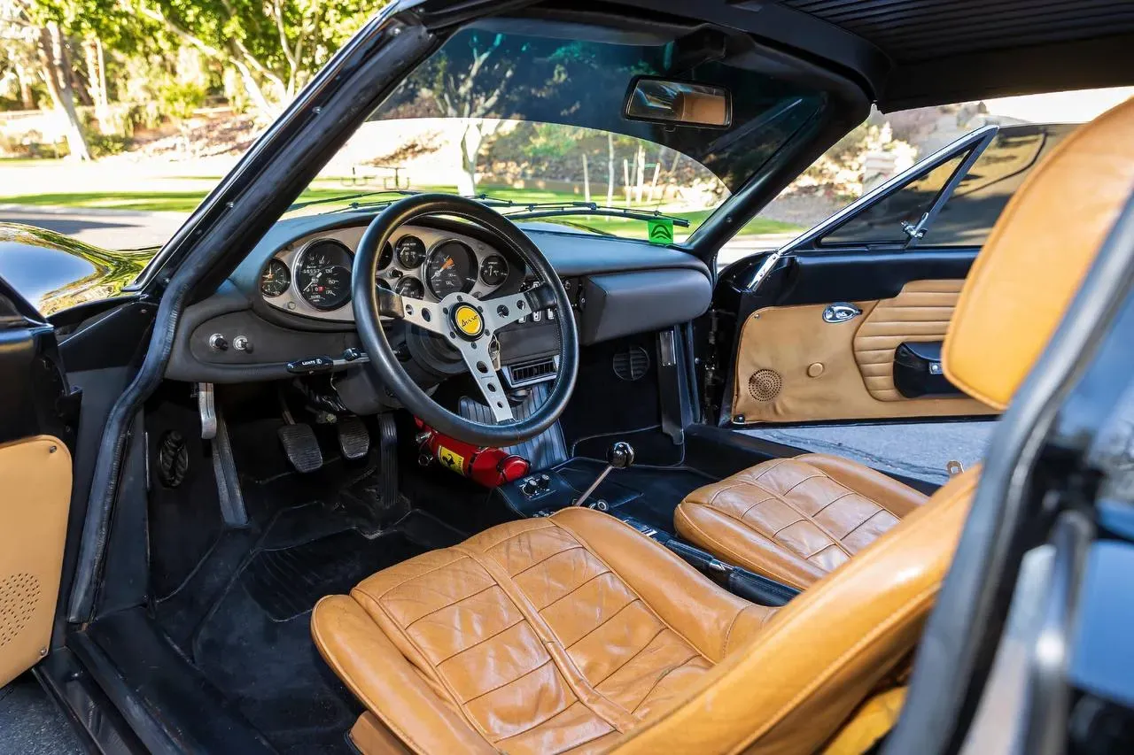 Interior del Ferrari Dino 246 GTS mostrando volante, cuadro de instrumentos y asientos