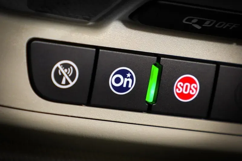 Panel de botones del servicio onstar en un vehículo, destacando el botón azul