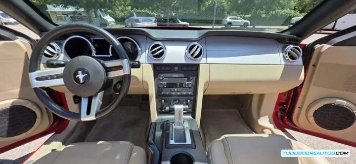 Interior del Ford Mustang S197 GT Convertible mostrando el tablero de instrumentos, la consola central y los asientos de piel color tan.