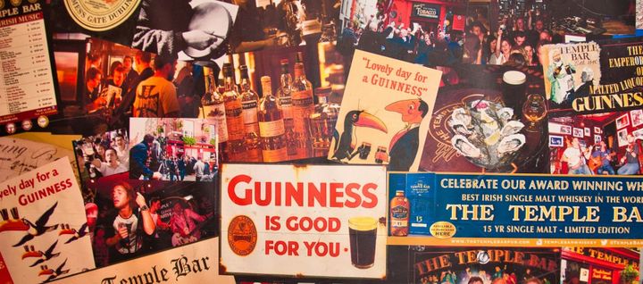 A wall covered with various Guinness and other adverts and photos likely from inside an Irish pub