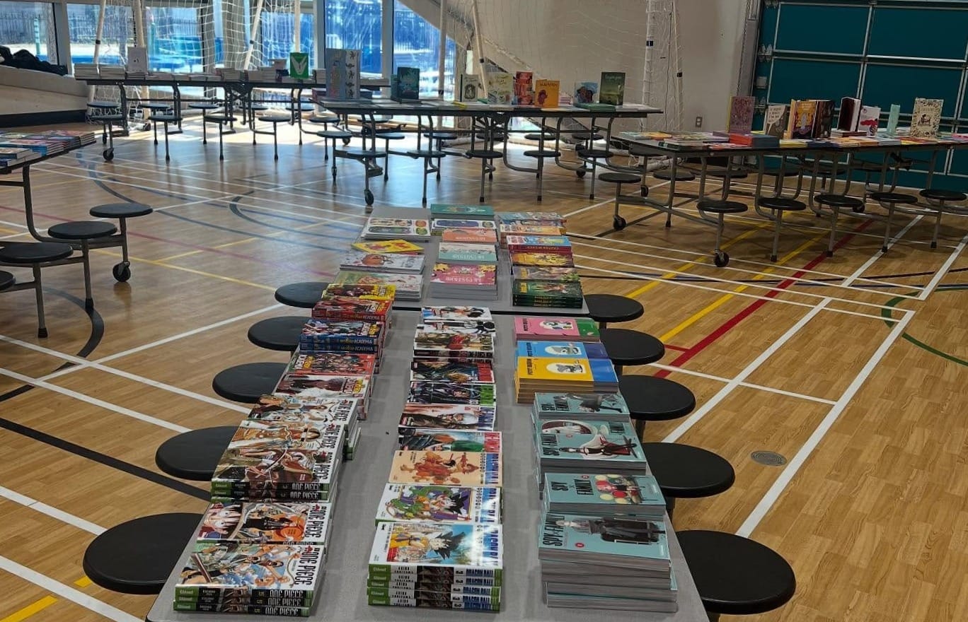 La photo d'un gymnase montre des tables où sont empilés des livres pour les jeunes.