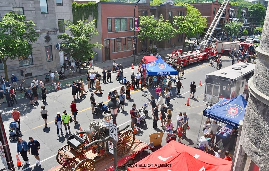 Vue de haut de plusieurs kiosques et véhicules de pompiers, dont certains historiques, éparpillés sur l'avenue Laurier.