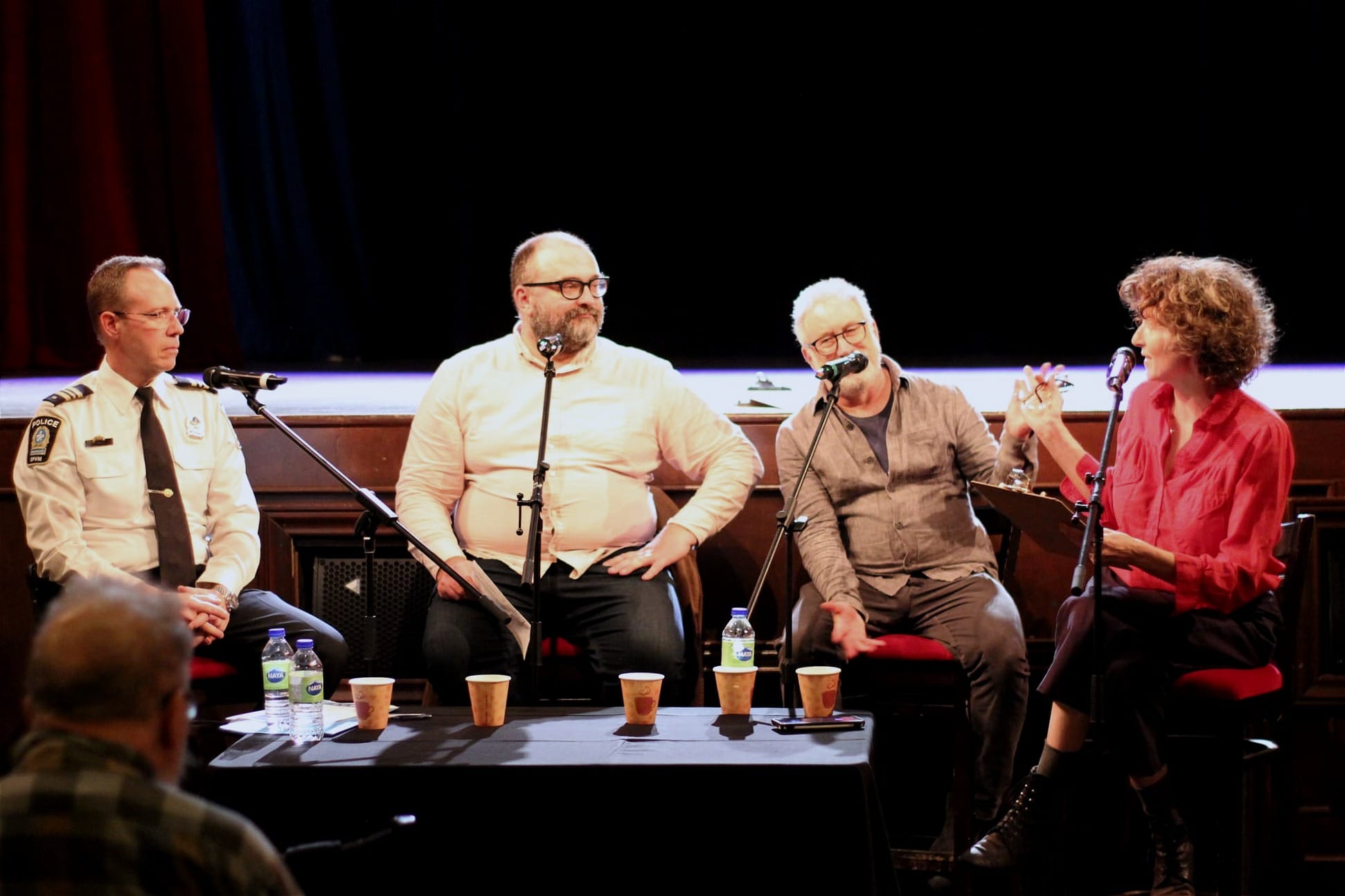 Les trois panélistes et l'animatrice de la soirée, Isabelle Anguita, assis devant le public.