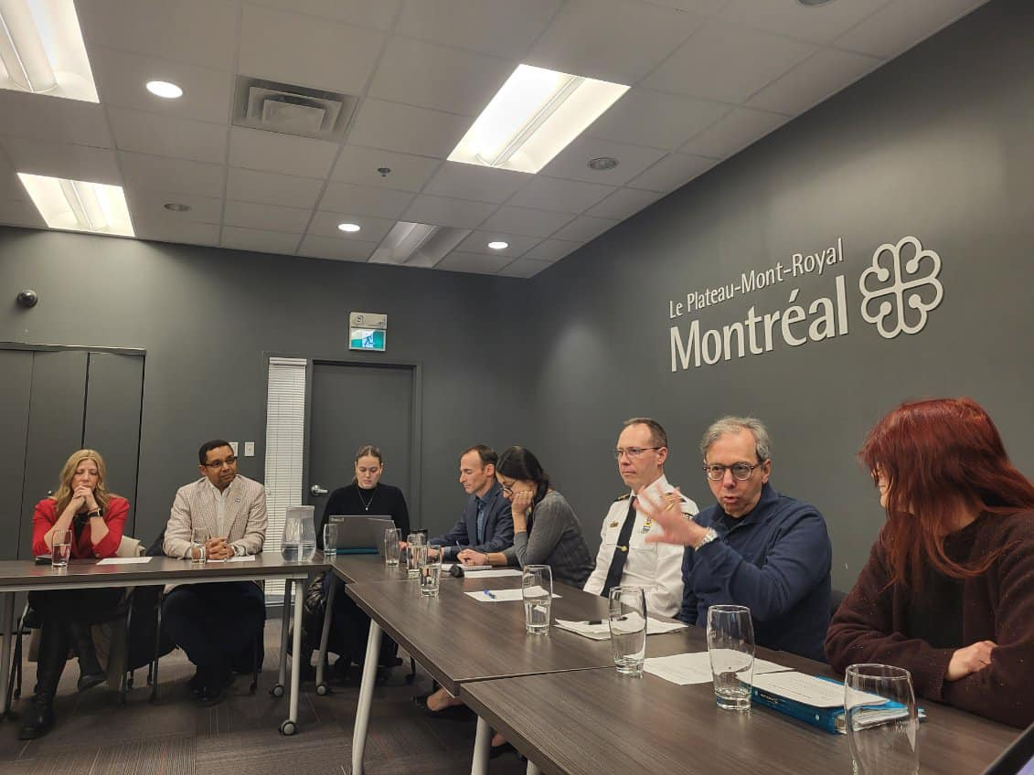 Huit personnes sont assises devant des tables dans les bureaux de l'arrondissement du Plateau-Mont-Royal.