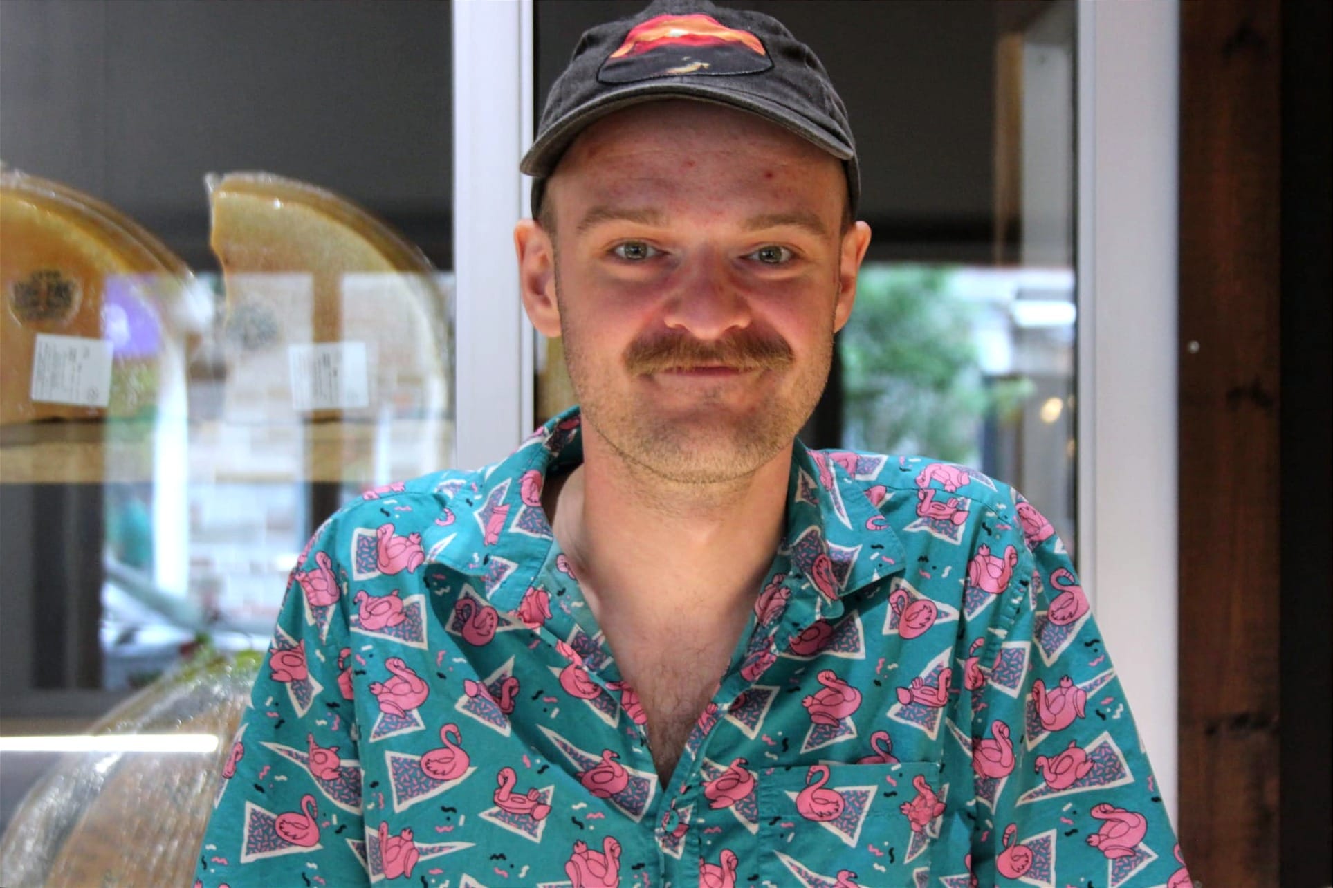 M. Chamberlain pose devant un réfrigérateur de fromage. Sa chemise à des motifs de flamants roses. 