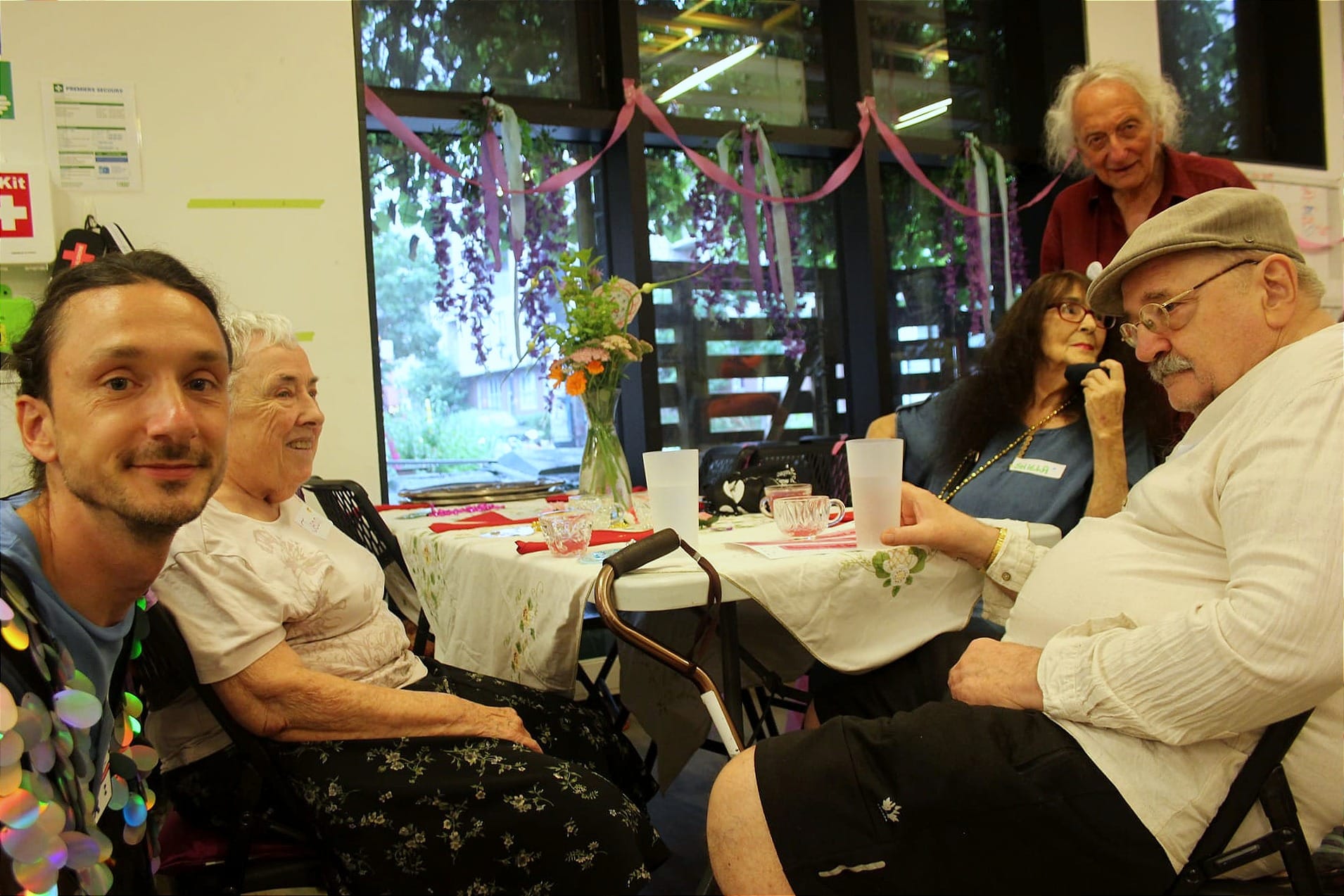 M. Liné est accroupi à côté des quatre personnes attablées.