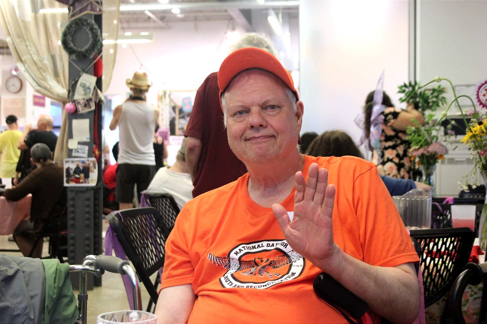 M. Perry pose assis, saluant la caméra de la main.