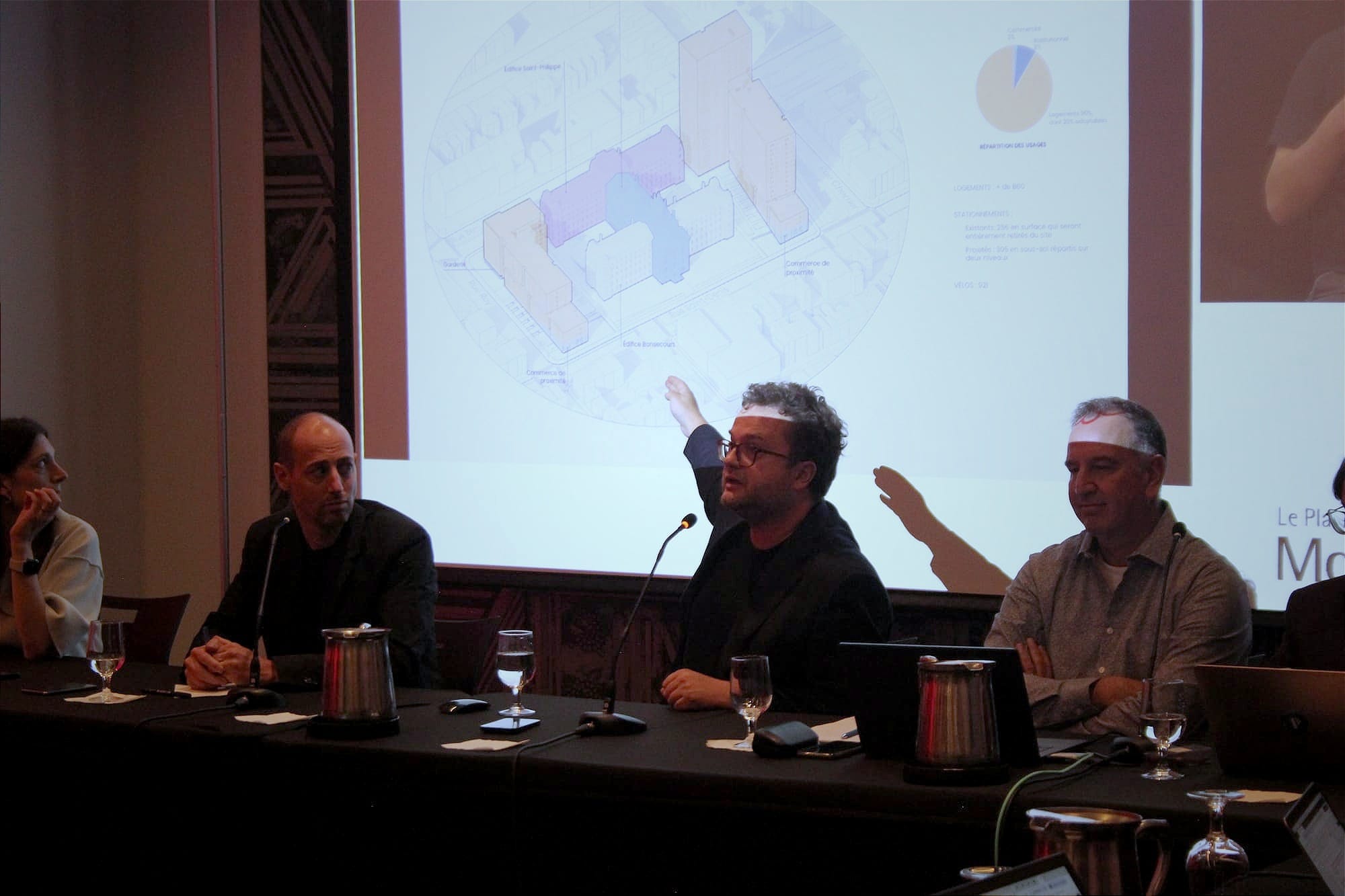 M. Barrieau, entouré des architectes et d'un urbaniste de l'arrondissement, pointe une diapositive illustrant les transformation projetées du site. 