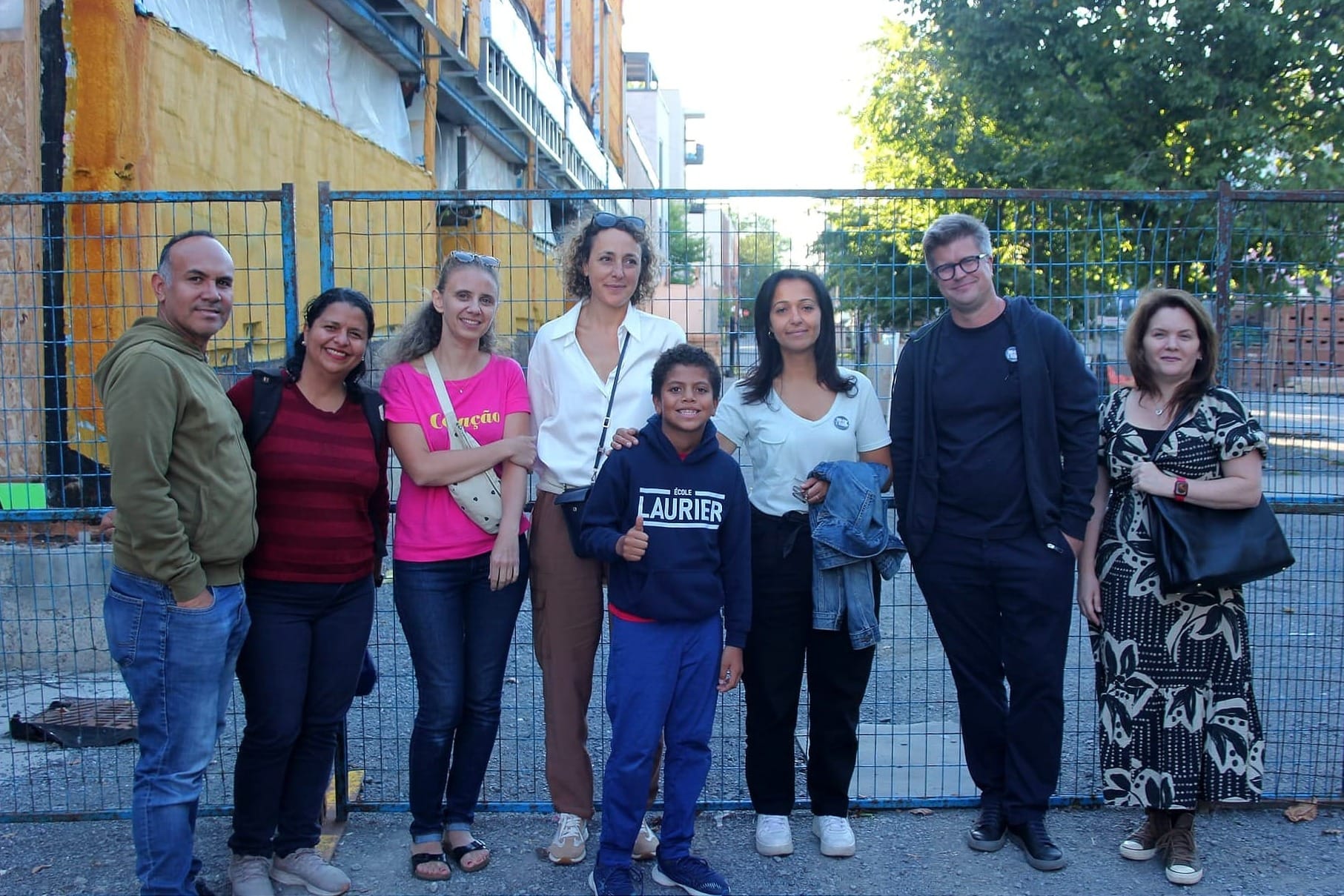 Huit personne posent devant la clôture du chantier, entourant Mme Ghazal.