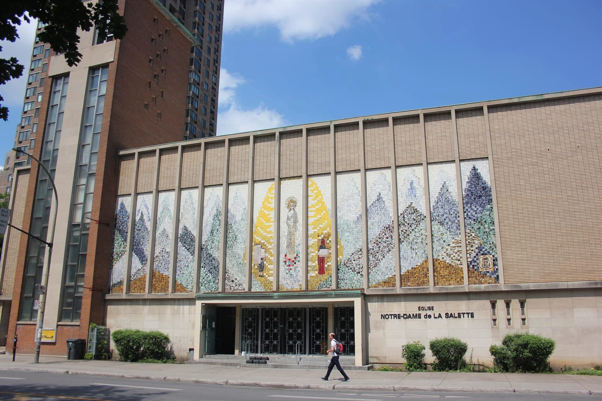 Un homme se déplace devant l'église Notre-Dame-de-la-Salette, lors d'une journée d'été ensoleillée. 