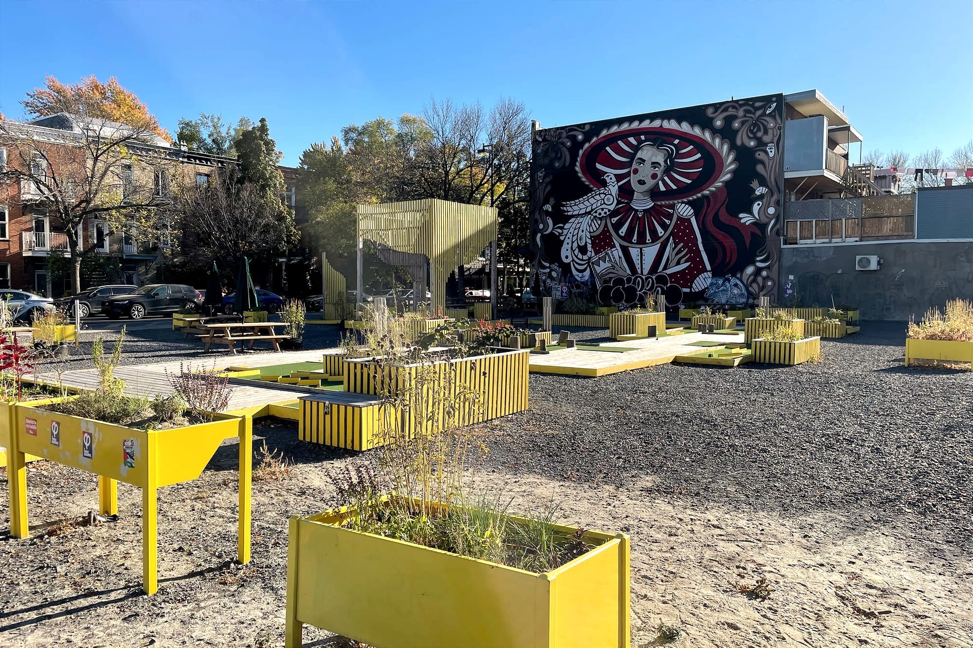 Vue du terrains, avec ses bacs jaunes, le parcours de mini-golf et la murale de style mexicain, de l'avenue Papineau. 