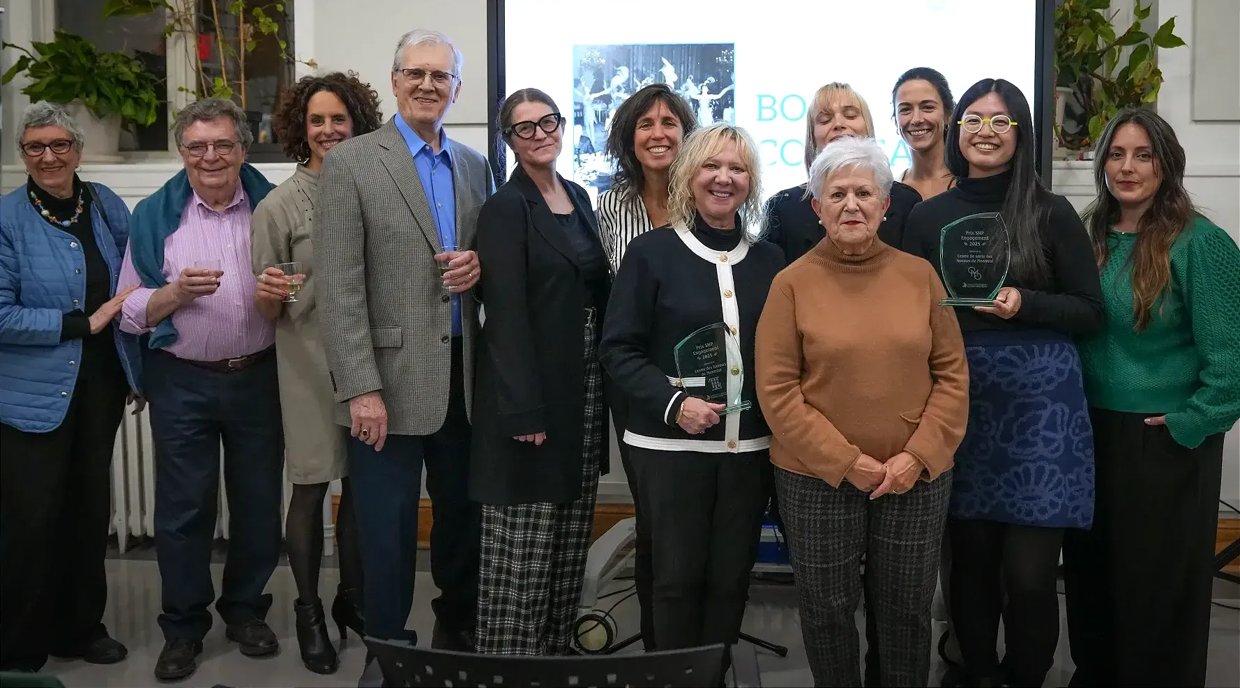 Les participants de la soirée posent pour une photo. Deux représentantes tiennent leur trophée. 