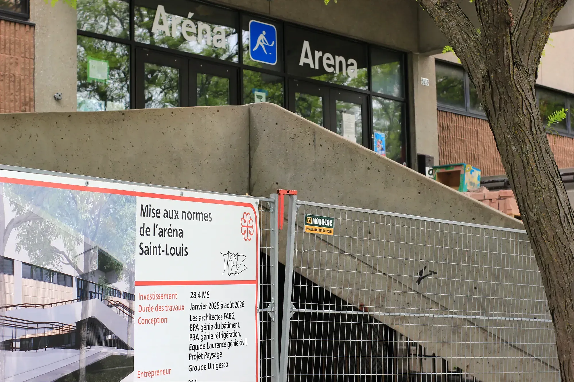 Une pancarte détaillant de la Ville de Montréal détaillant les travaux est accrochée à une clôture, devant l'entrée de l'aréna.