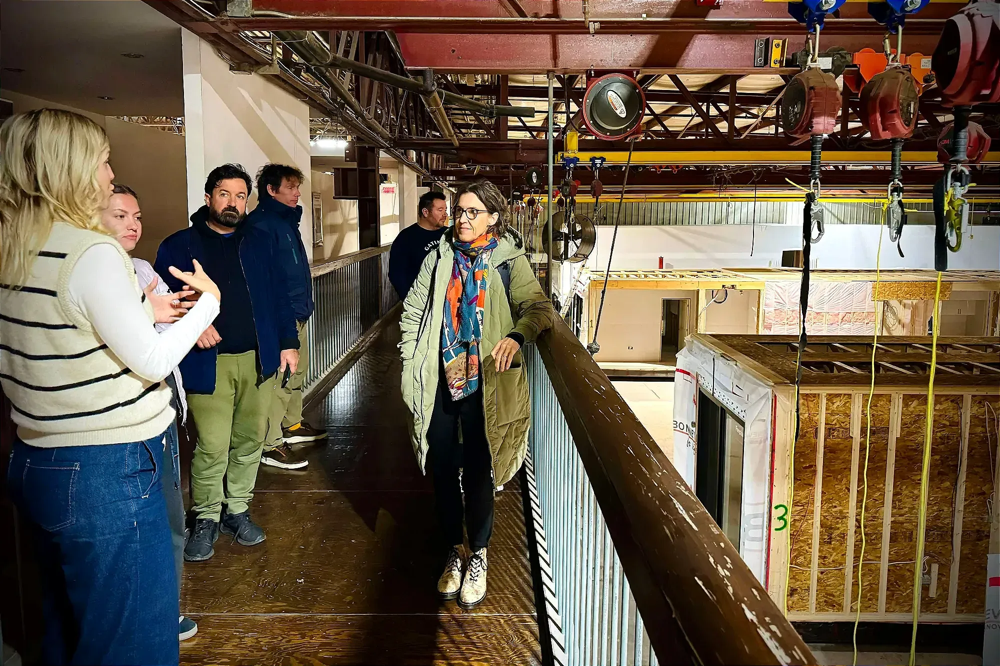 Quelques personnes discutent sur une passerelle, alors qu'on voit quelques modules préfabriqués à leur droite.