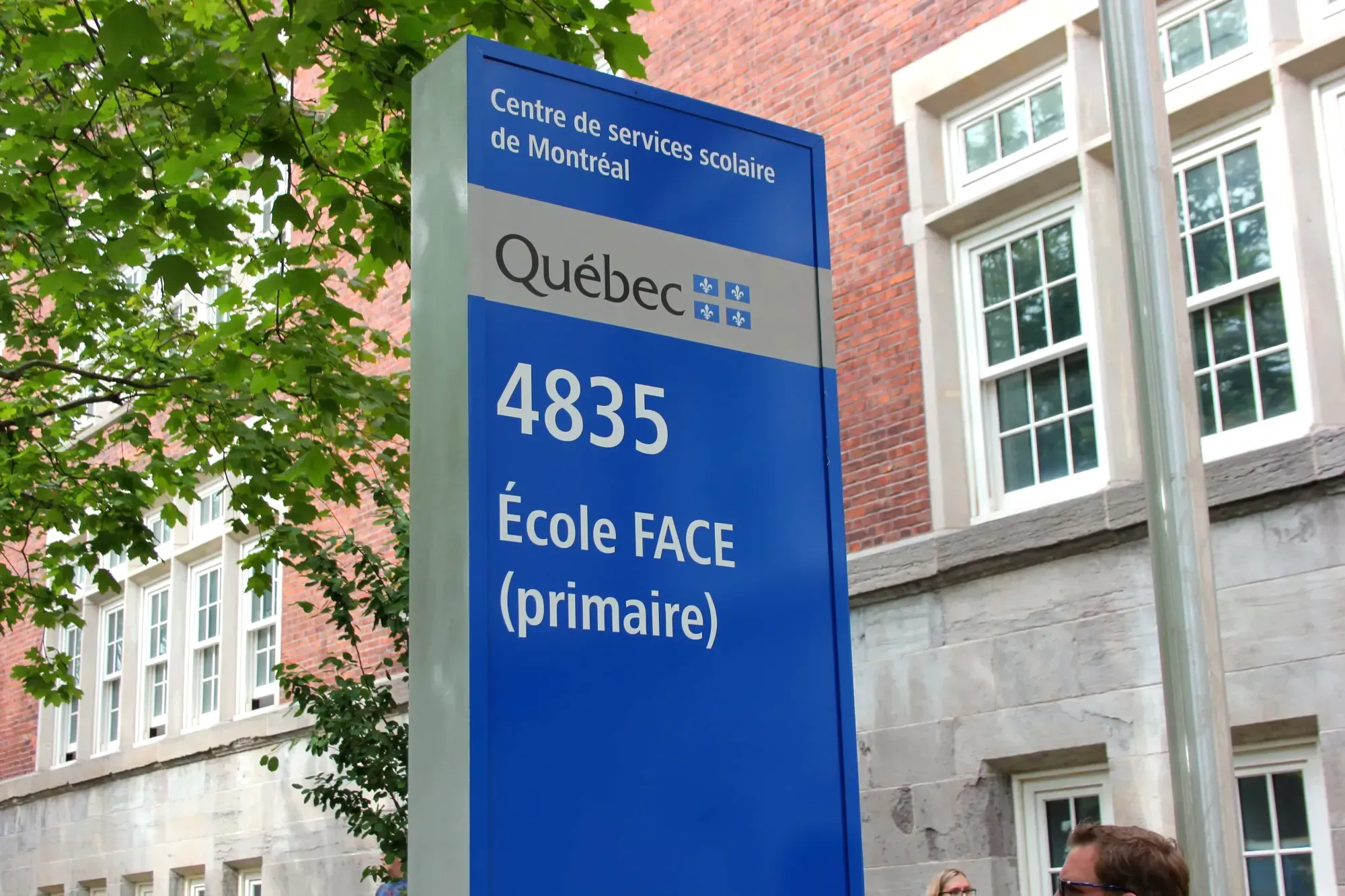 Le panneau bleu du CSSDM, érigé devant le bâtiment de l'avenue Christophe-Colomb, indiquant le nom et l'adresse de l'école (primaire) FACE. 