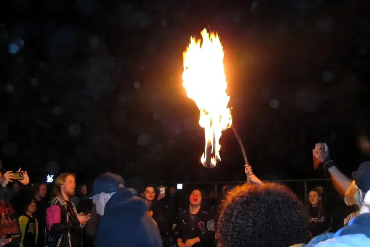 Un flamme intense brille au centre d'une foule. 