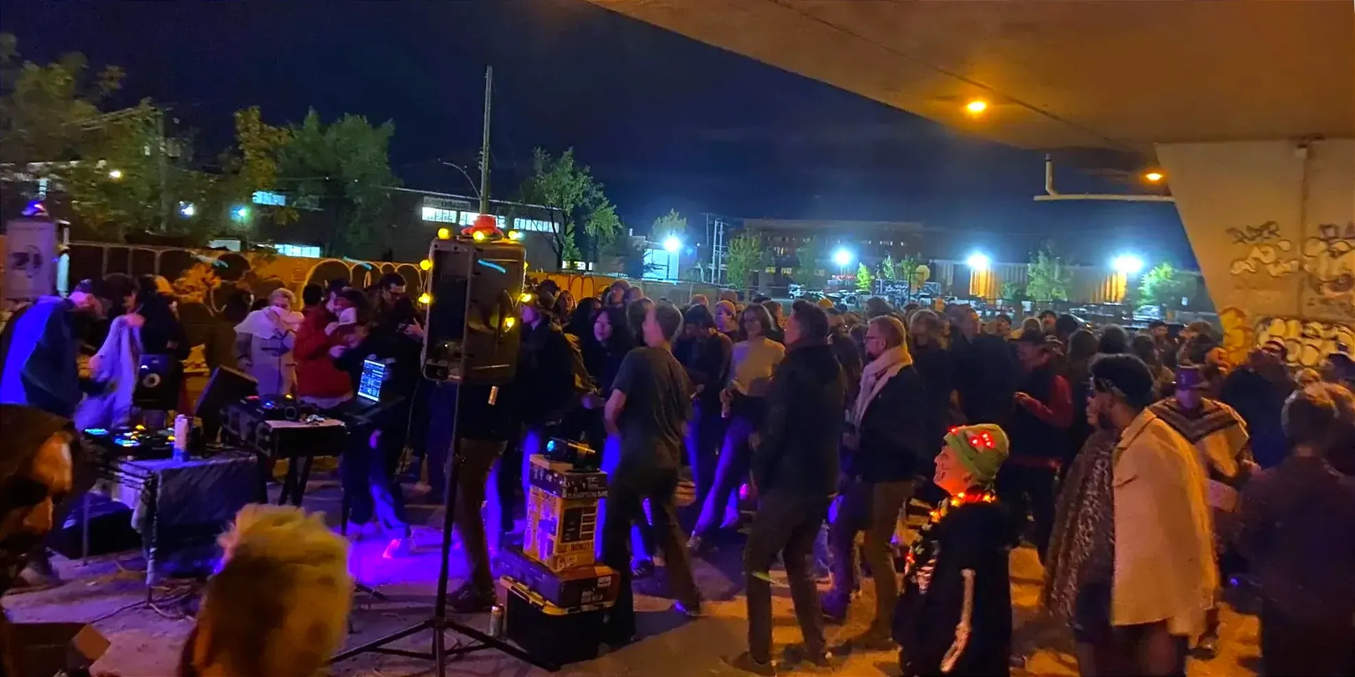Un DJ est en performance devant une foule de quelques centaines de personnes.