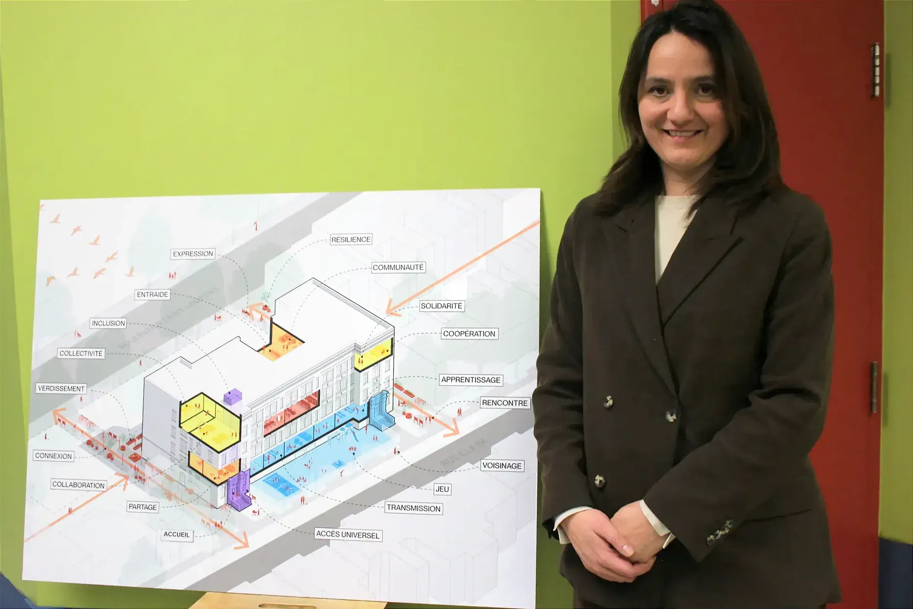 Mme Hudon-Huot pose à côté du plan de l'immeuble. 