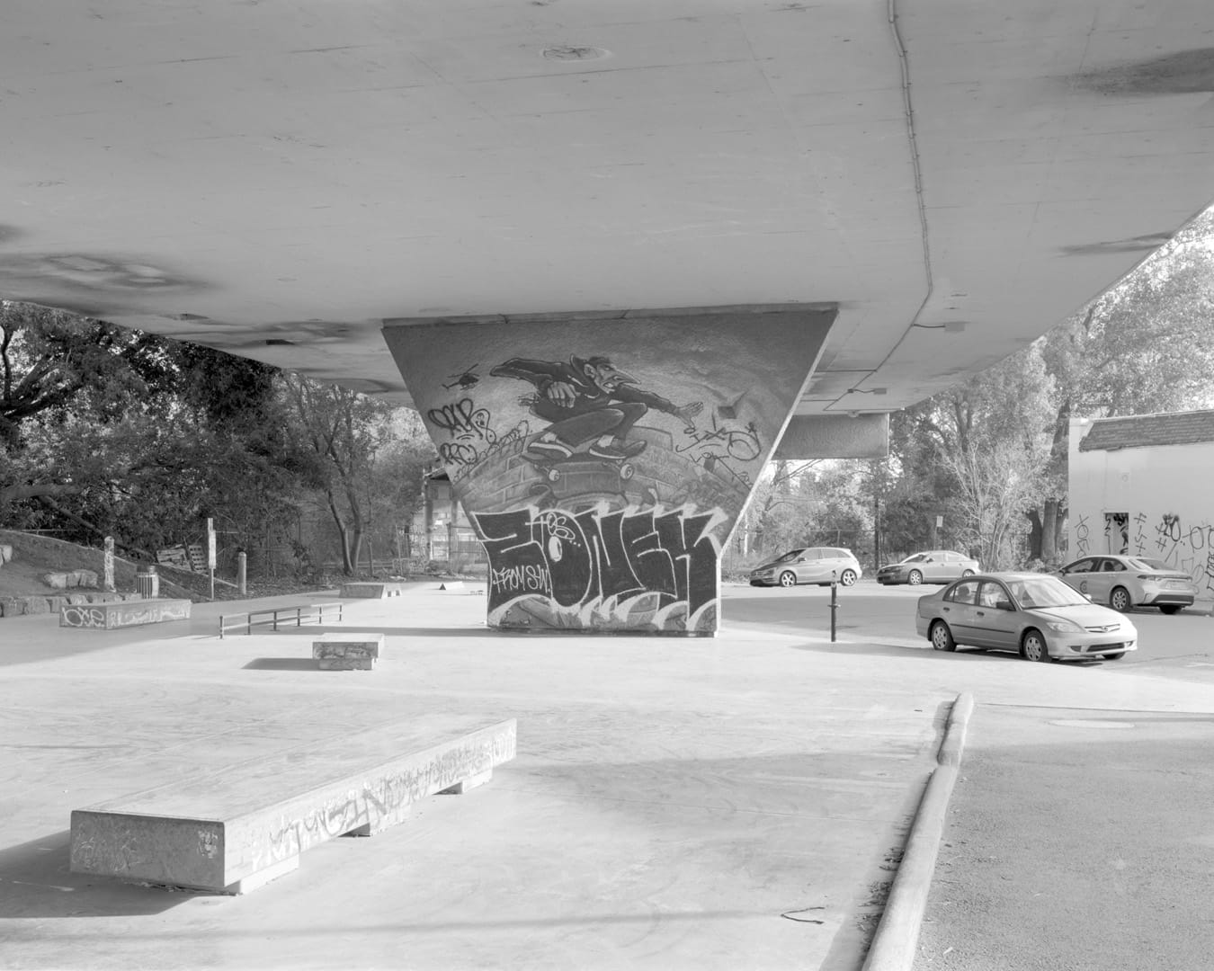 Une photo en noir et blanc avec un pilier du viaduc où l'on aperçoit le dessin d'une personne sur une planche à roulette.