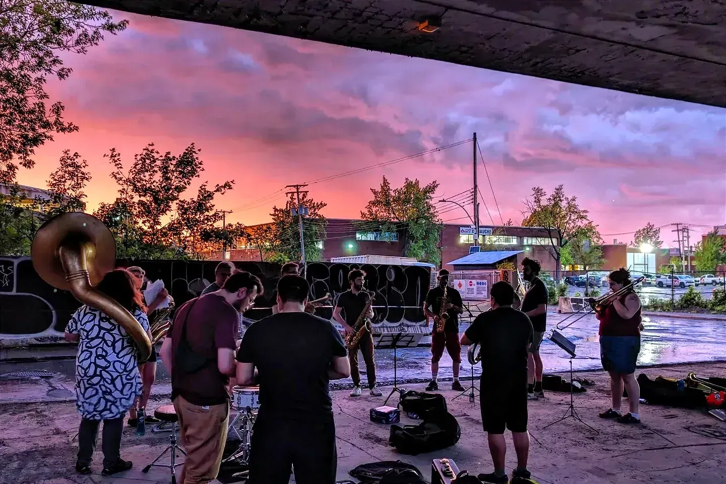 La dizaine de musiciens est placée en cercle sous la viaduc, dans le secteur Bellechasse, à la lumière rosée du soleil couchant.