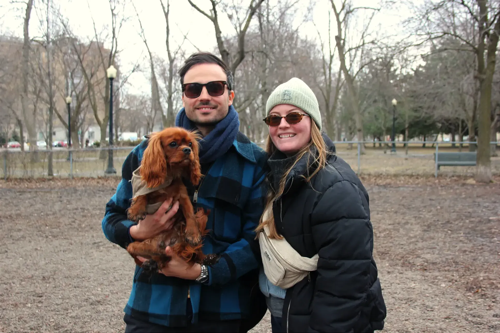Bérangère et Loïc posent dans le parc pour petits chiens, alors que Loïc tient Simone dans ses bras.