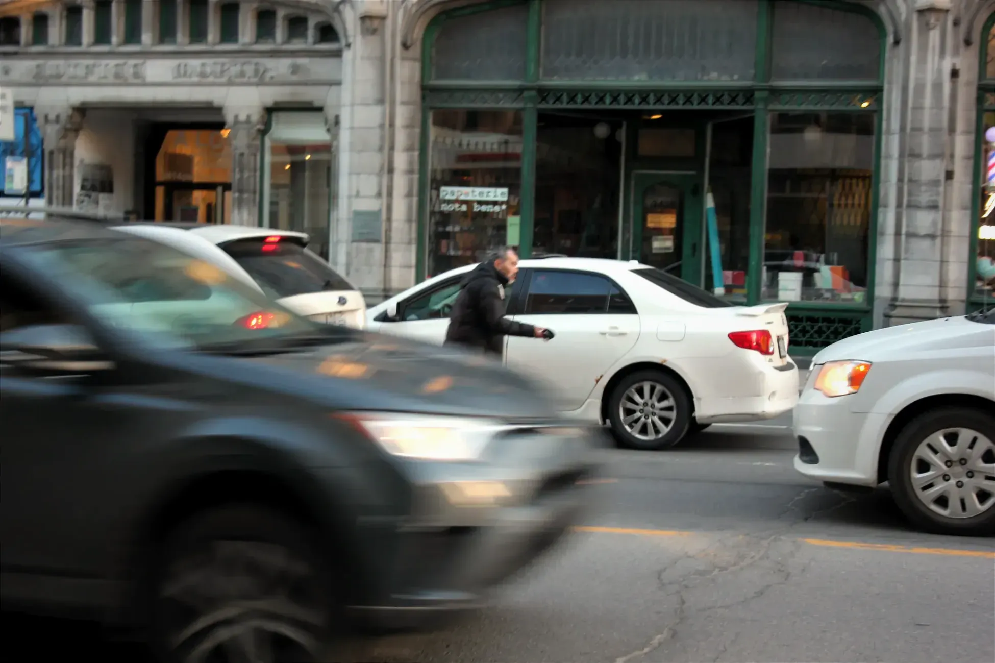Un homme circule au loin entre deux rangées de voitures sur l'avenue achalandée. 