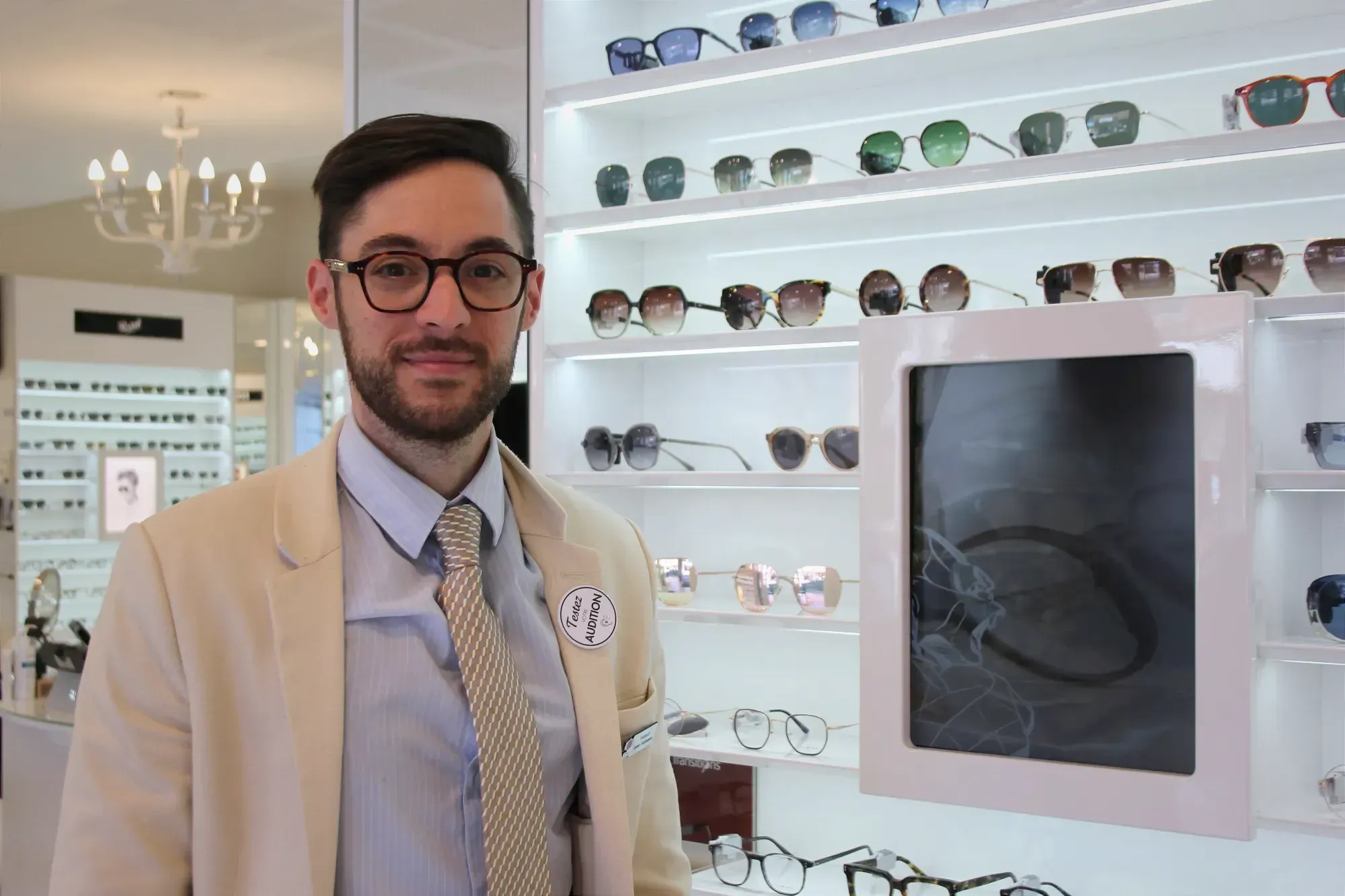 M. Thibault pose devant les étalages de la lunetterie pour laquelle il travaille. 