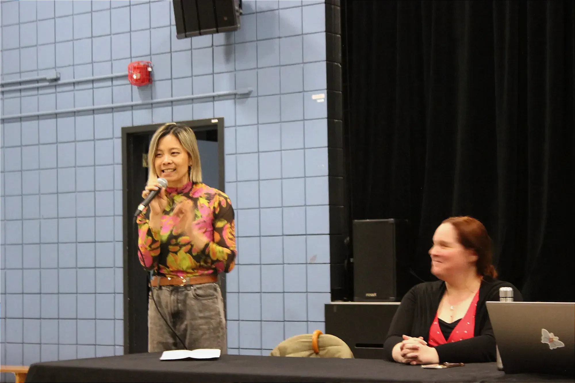 Mme Wong se tient debout, microphone à la main. 