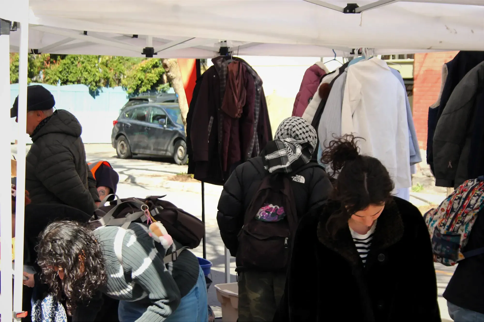 Plusieurs individus scrutent le contenu du vide-grenier solidaire.