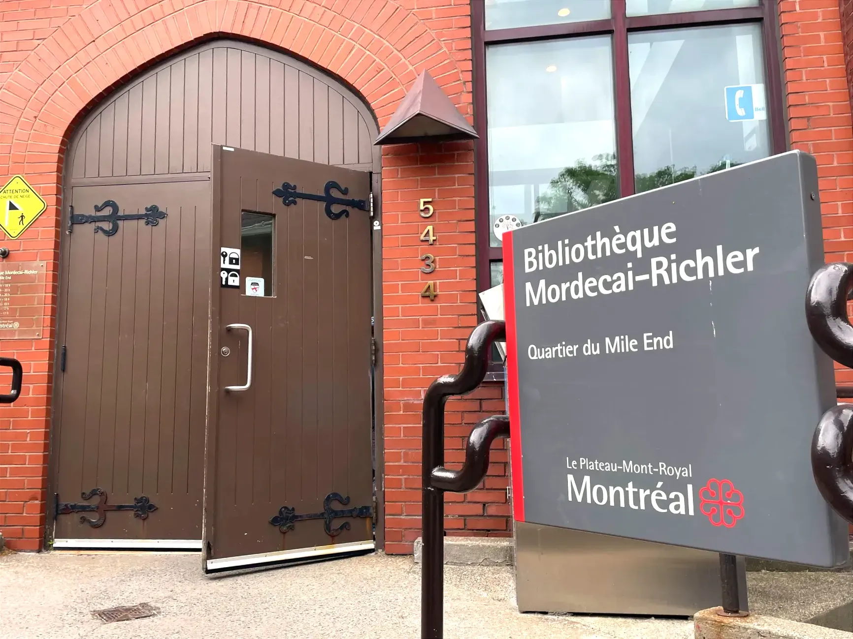 Vue de la porte d'entrée de la bibliothèque avec la panneau indiquant le lieu, à la droite du cadre.