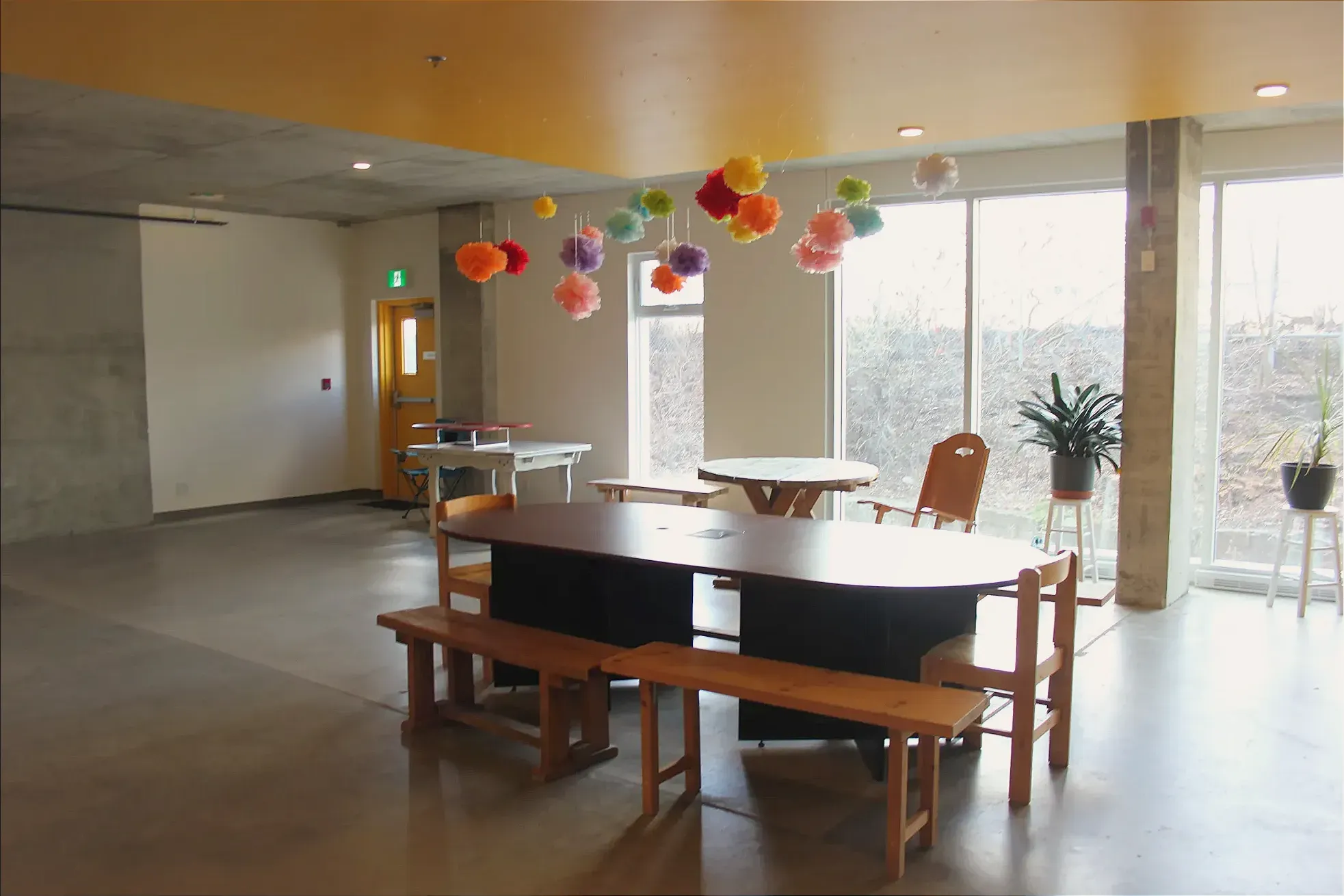 Des décorations multicolores en papier de soie sont suspendues au-dessus de la table de la salle communautaire vide.