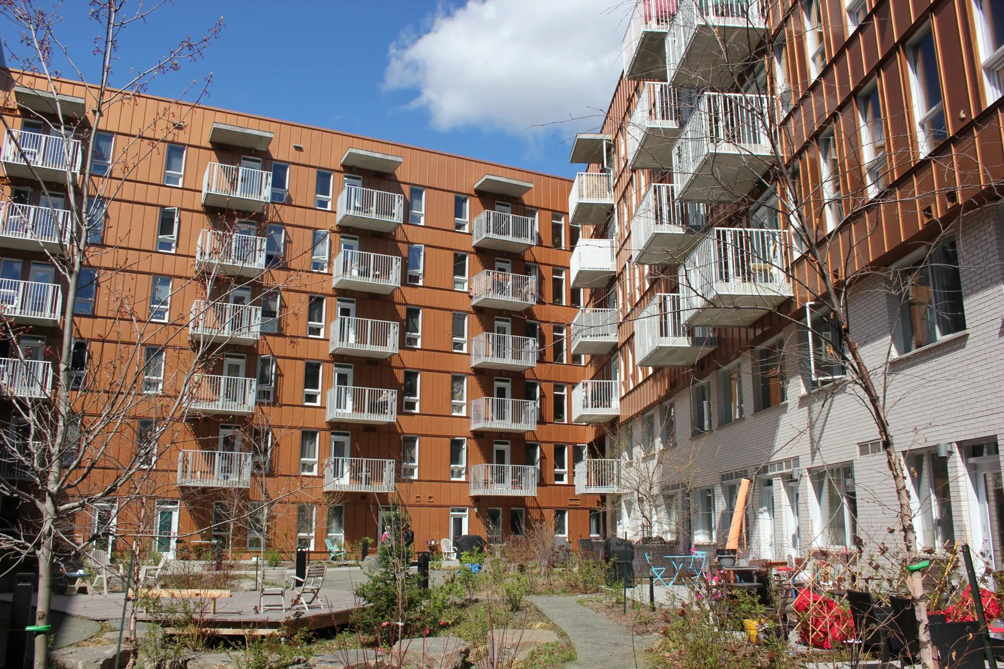Un bâtiment orange et blanc de six étages, vu de la cour intérieure, sous le soleil de printemps.