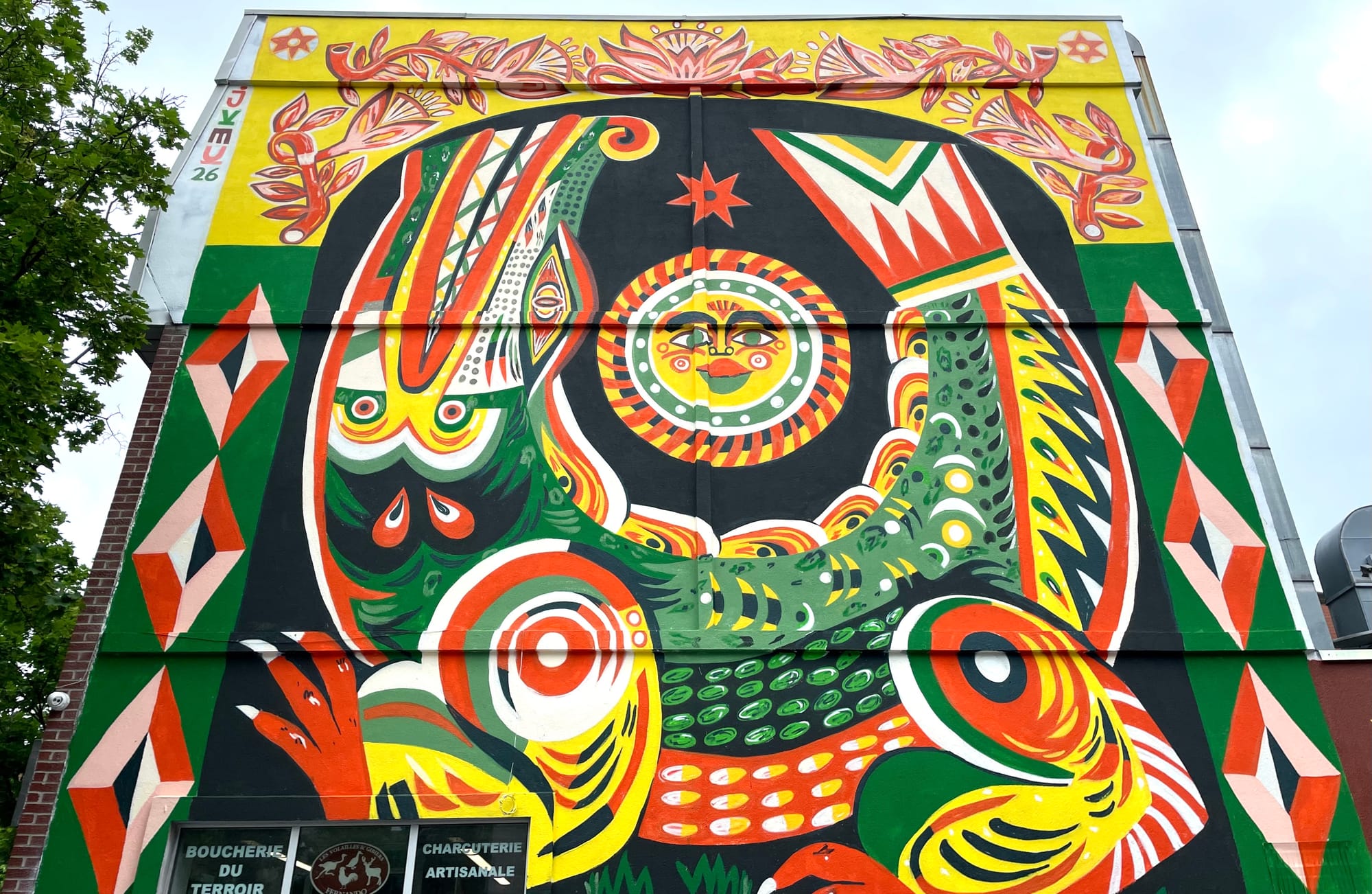 Un alligator en demi-cercle, peint en vert, orange, jaune, blanc et noir, avec plusieurs motifs.