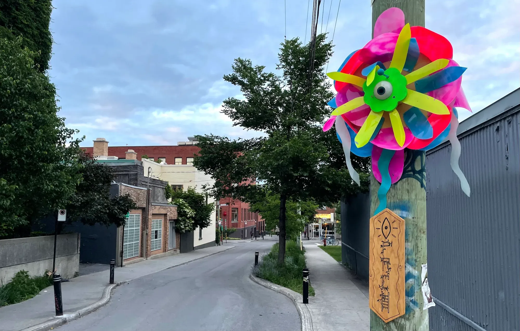Une très grande fleur en ce qui semble être du plastique et aux couleurs néons est accrochée sur un poteau en bois de la rue Marie-Anne.