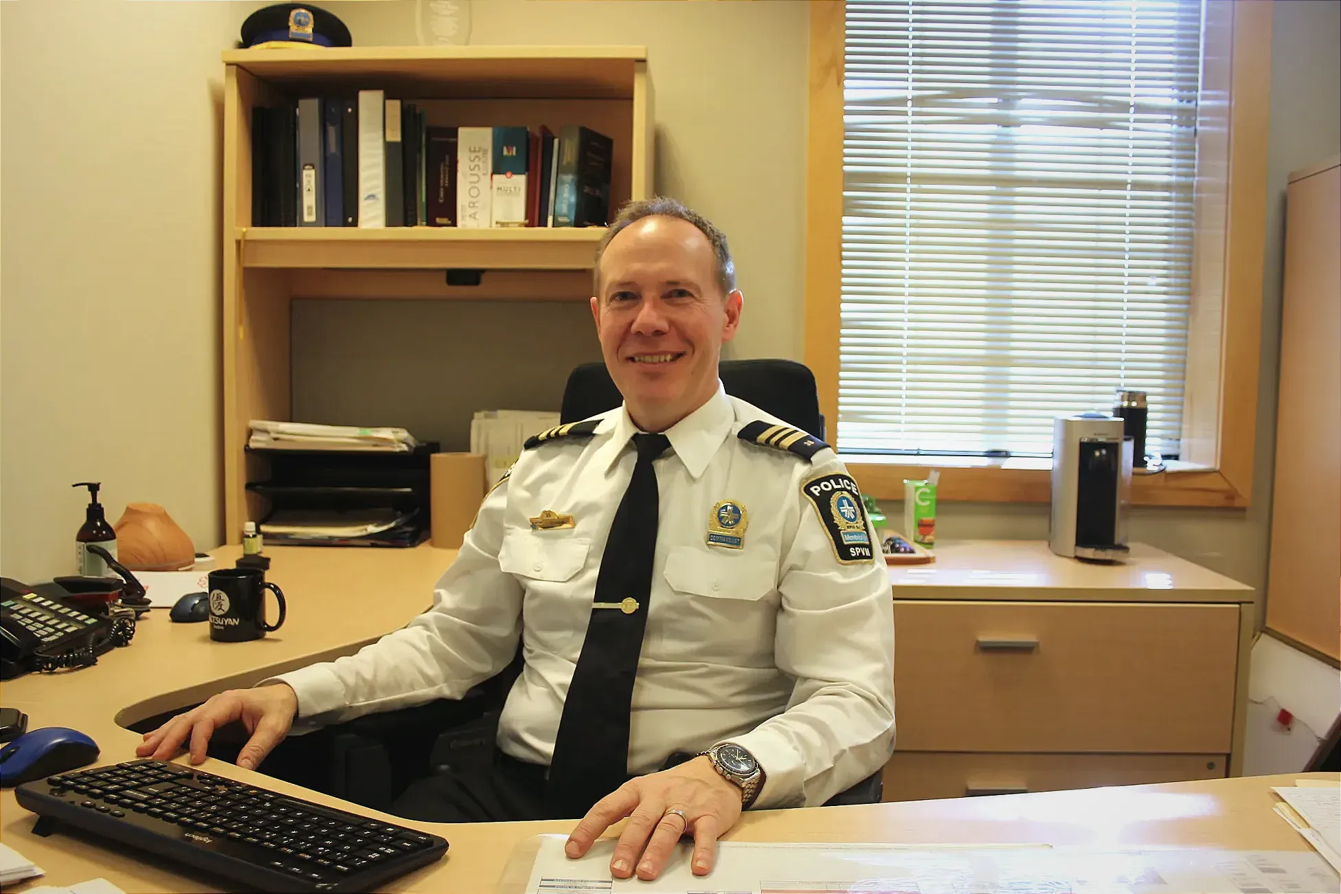 Le commandant Malo poste, assis derrière son bureau au poste de quartier 38.