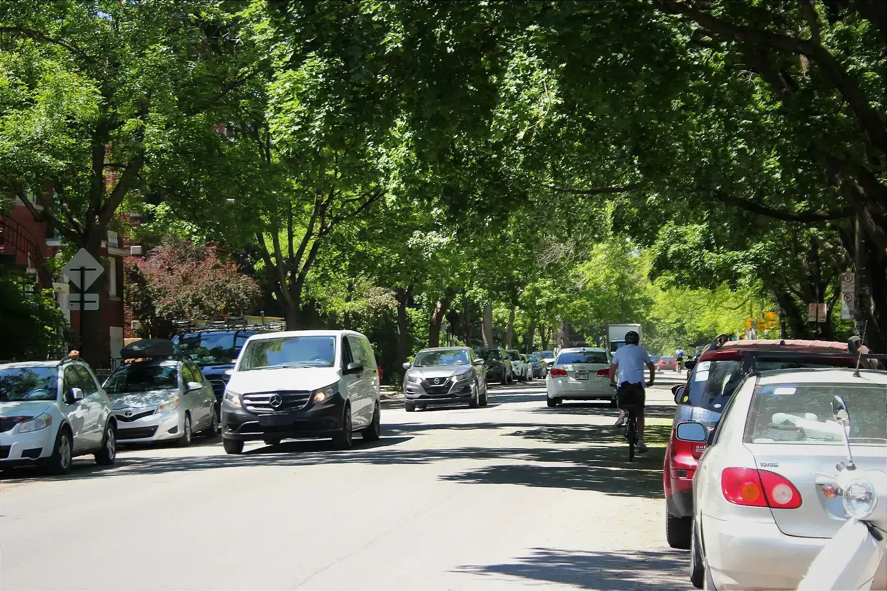 Un cycliste se dirigeant vers le nord sur la rue Fullum, aux abords du parc Baldwin, croise quelques voitures en sens inverse.