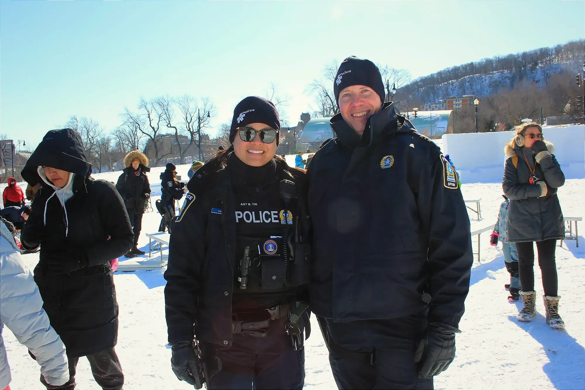 Les deux agents posent dans un parc Jeanne-Mance enneigé, parmi les participants du carnaval.