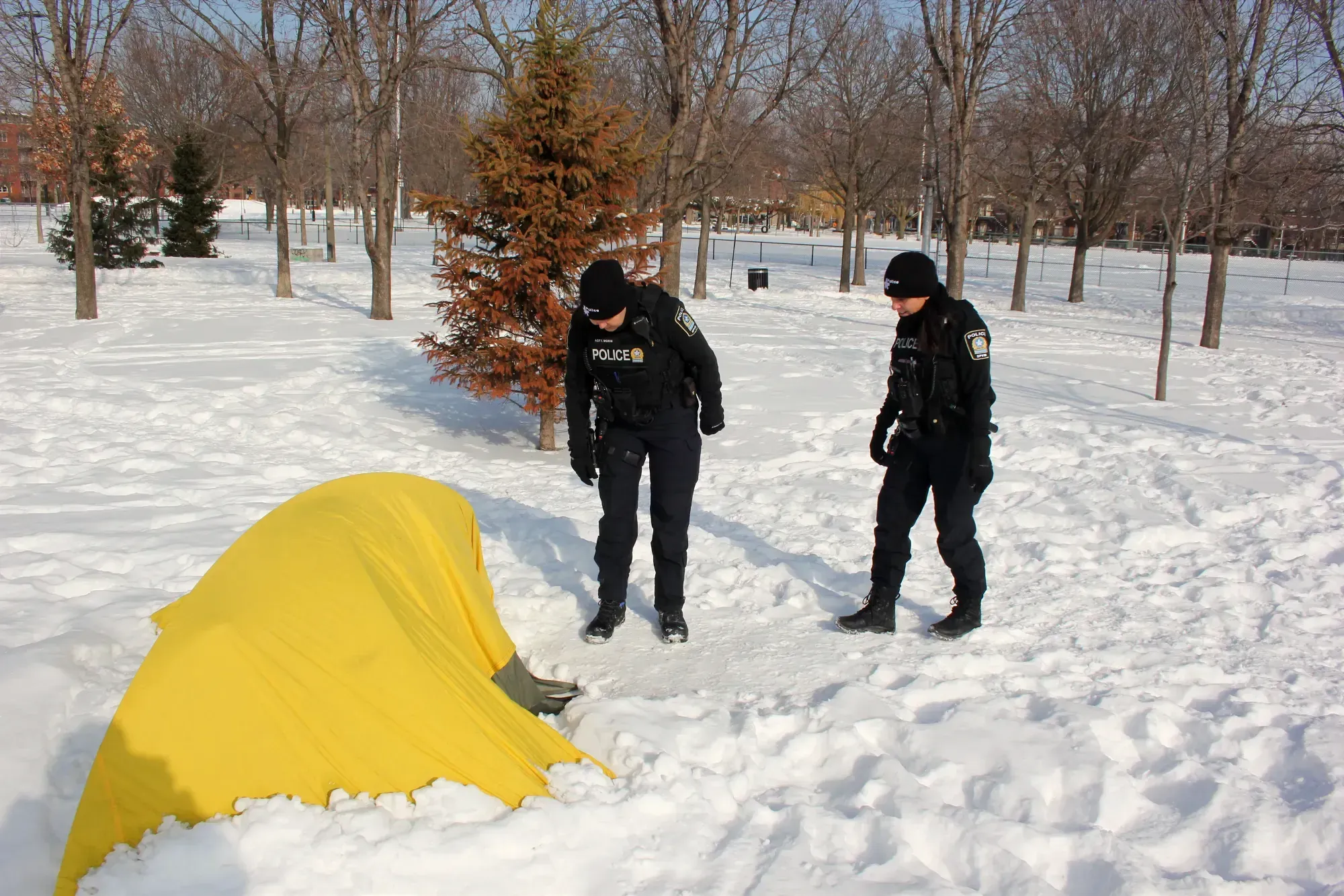 Les agentes faisant face à une tente jaune, installée dans la neige, sont à l'écoute.